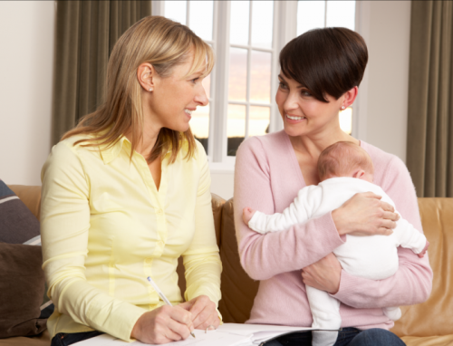 mother cuddling her baby while talking to a pediatrician