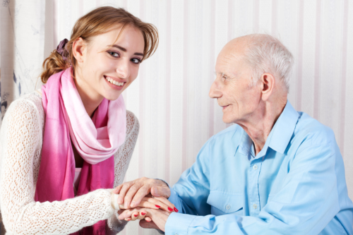 elderly man holding his caretaker's hands